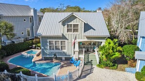 Ein zweistöckiges Haus mit Swimmingpool, Terrasse und einem umzäunten Patio.