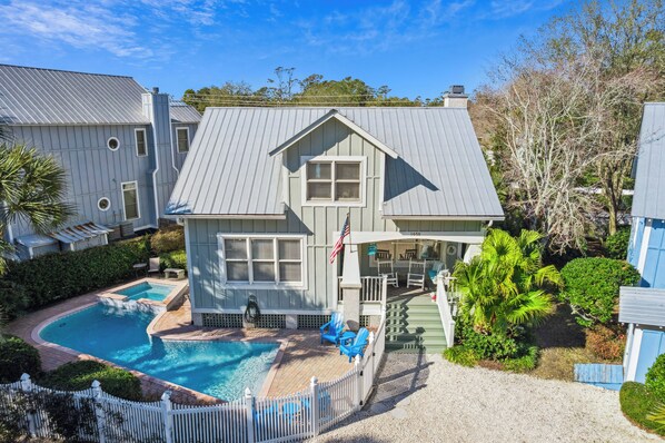 A two-story house with a swimming pool, a deck, and a fenced patio area.