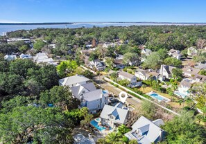 A residential area with houses, a swimming pool, and a lighthouse in the background.