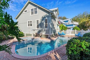 A two-story house with a swimming pool, a white picket fence, and a blue exterior.