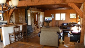 Ein rustikales Cabin-Interieur mit einem Holzesstisch, einer Couch und einem Fernseher im Hintergrund.