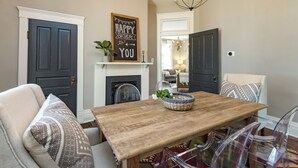 A dining area with a wooden table, clear chairs, a fireplace, and a 'Happy Birthday' sign. - The Peachtree House  (Nashville)