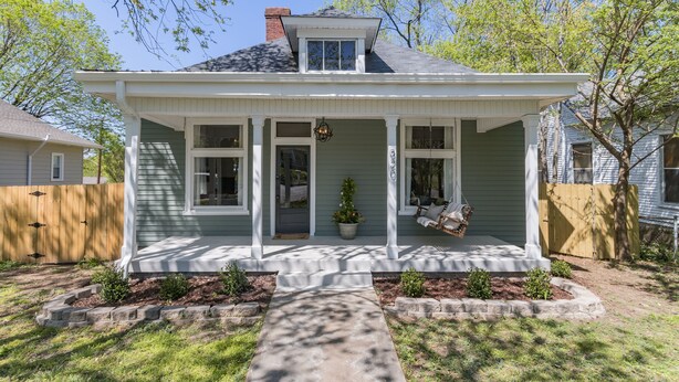 A two-story house with a front porch, a small garden, and a wooden fence. - The Peachtree House  (Nashville)
