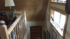 A wooden staircase with a handrail, a small window with decorative items, and a wall-mounted shelf.