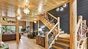 A spacious living area with a wooden staircase, a fireplace, and a stone wall.
