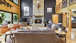 A cozy living room with a stone fireplace, leather sofas, and a television.