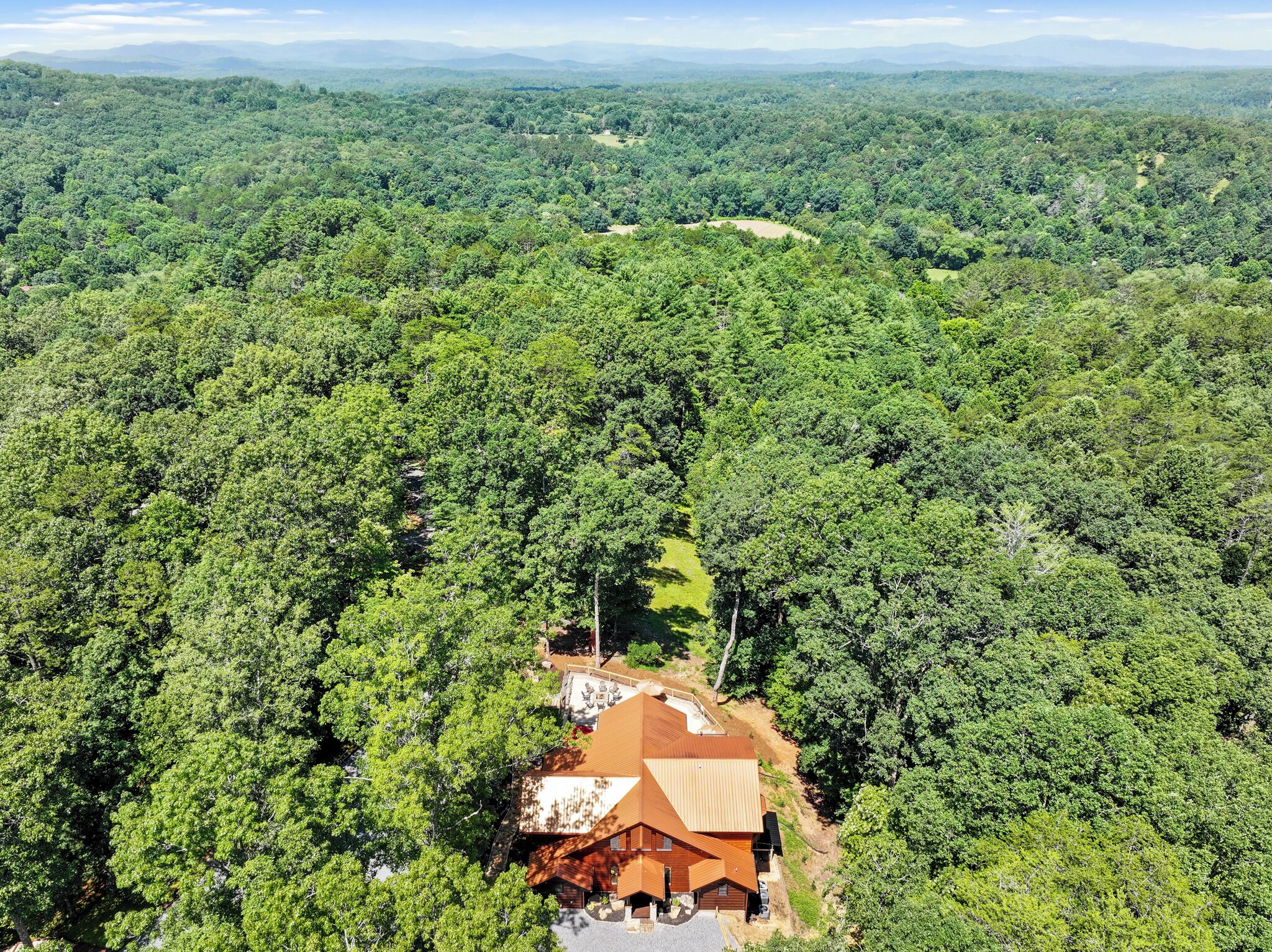 A large, single-story building surrounded by dense forest, with a clear view of the surrounding landscape.