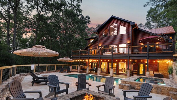 A log cabin with a swimming pool, outdoor seating, and a fire pit.