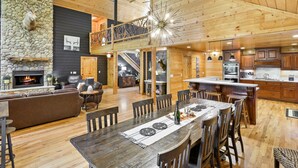 A spacious wooden interior with a dining area, kitchen, and a fireplace.