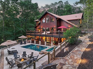 A two-story log cabin with a swimming pool, outdoor seating, and a stone pathway. - Luxe Mountain Resort - Heated Pool & 14ft Hot Tub (Morganton)