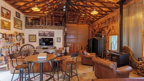 Un interior rústico con vigas de madera a la vista, una chimenea, muebles de cuero y una estantería.