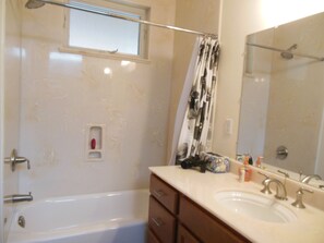 Een bad/douchecombinatie, een haardroger, handdoeken