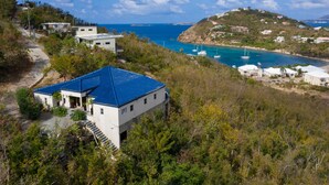 A coastal property with a blue-roofed building, a clear view of the sea, and a hillside with scattered houses. - Samba Azul 2 br2 ba ensuites w ACs private pool beautiful sunsets &new GENERATOR (St.John)