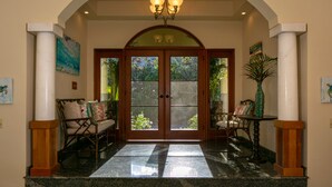 A grand entrance with a glass door, a chandelier, and a bench with cushions. - Samba Azul 2 br2 ba ensuites w ACs private pool beautiful sunsets &new GENERATOR (St.John)