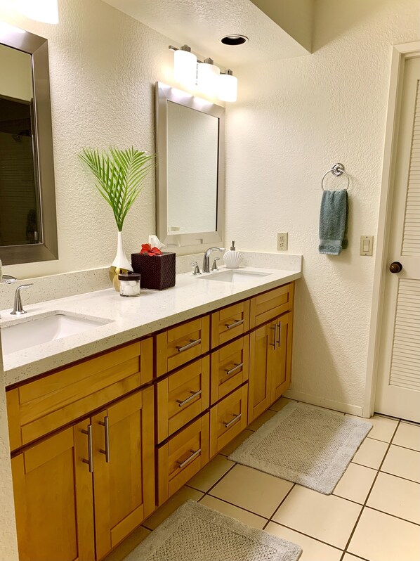A bathroom with a double sink vanity, wooden cabinets, a large mirror, and a towel rack.