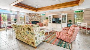 A spacious living room with a sofa, chairs, a TV, and a stone wall. - Waterfront 5B+den Bethany Lakes, POOL,Pickleball,Gym, 5 min to beach, dogs ok (Bethany Beach)