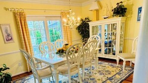 A dining area with a white table and chairs, a floral rug, and a cabinet with glass doors. - Waterfront 5B+den Bethany Lakes, POOL,Pickleball,Gym, 5 min to beach, dogs ok (Bethany Beach)