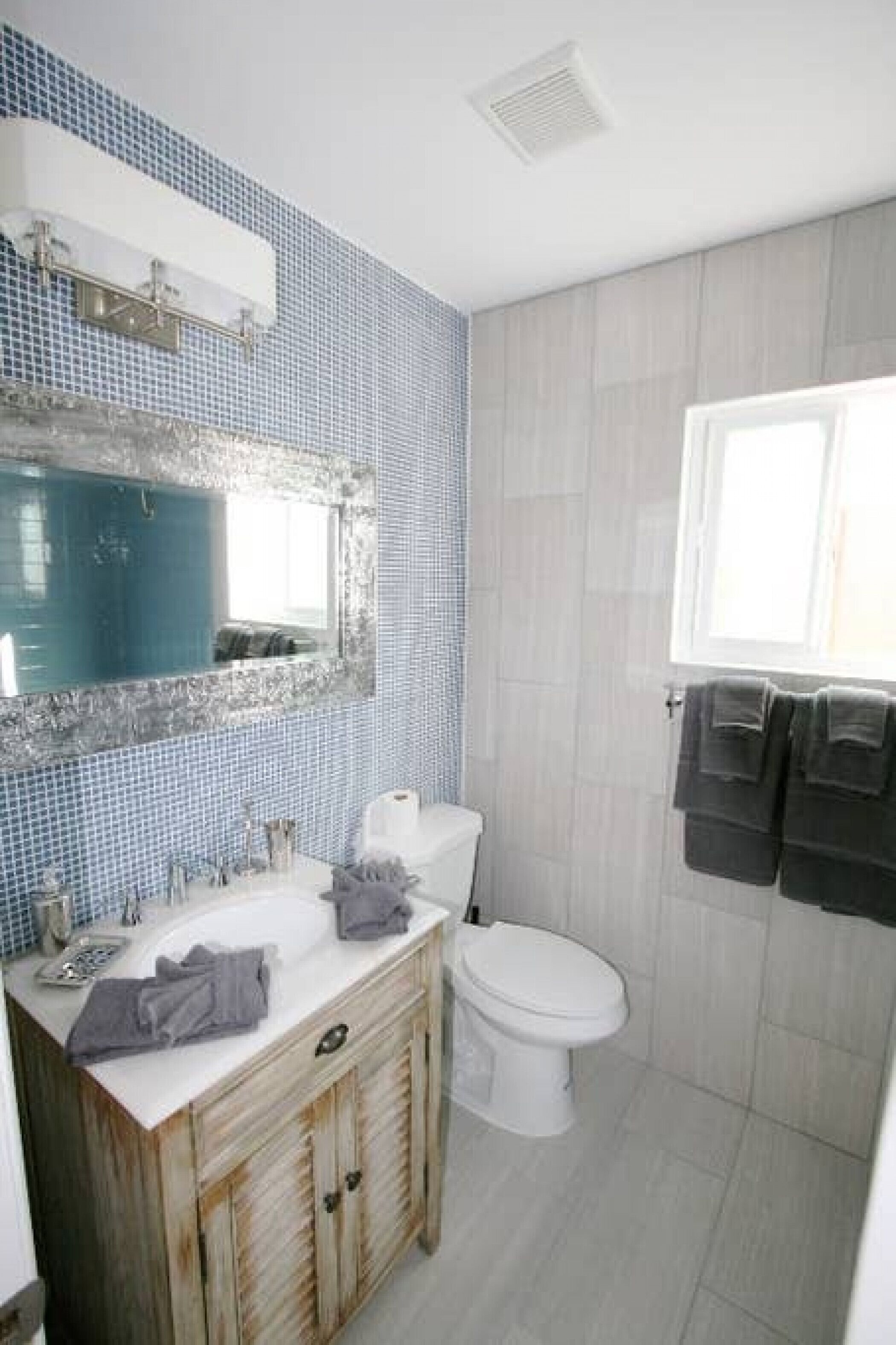 Un bagno con lavandino, specchio, WC e portasciugamani.
