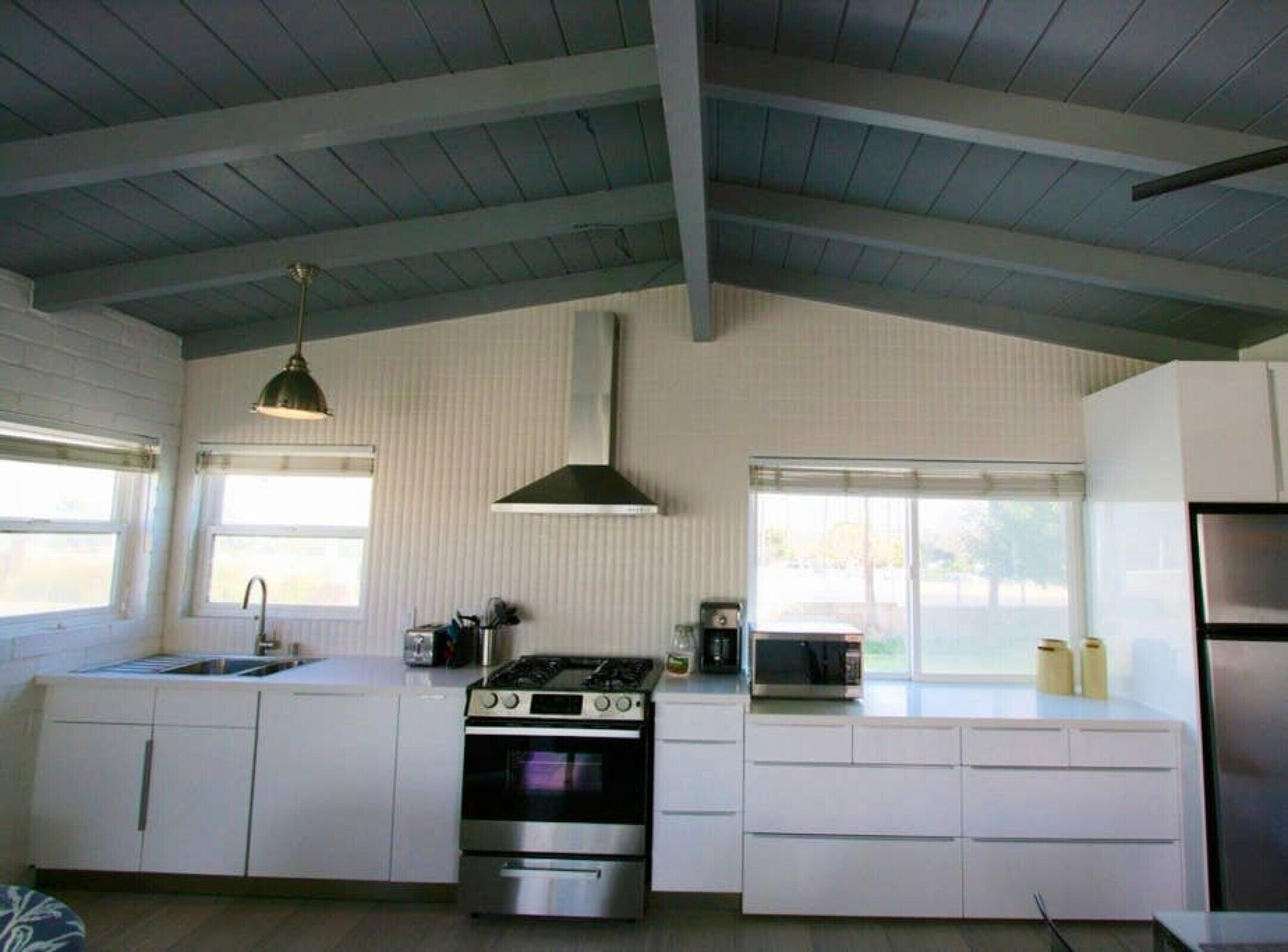 A kitchen with white cabinets, a stainless steel stove, a microwave, and a sink.