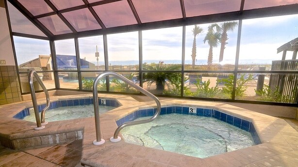 A hot tub area with a view of the beach and palm trees.