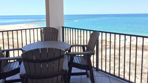A balcony with a table and chairs overlooking a beach.
