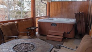 A hot tub on a wooden deck with wicker furniture and a stone fire table. - The Stemwinder Chalet by Simply Kimberley (Kimberley)