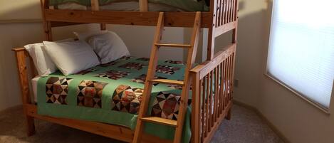 A bunk bed with a ladder, a green blanket, and pillows.