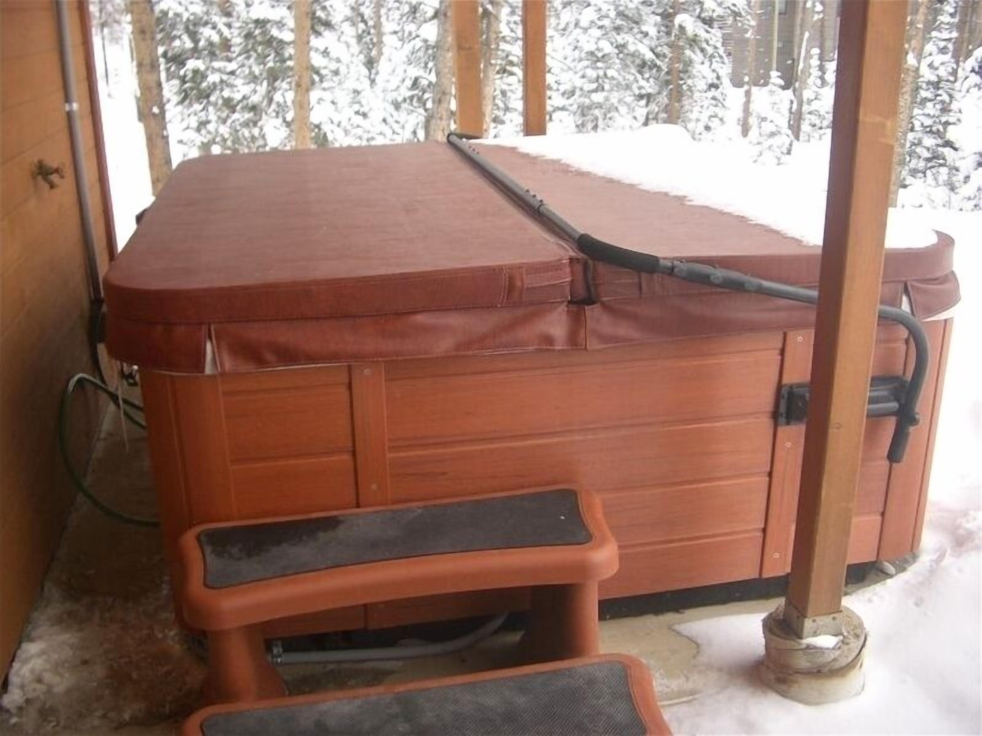 A hot tub with a wooden exterior, a bench, and a hose.