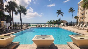 A swimming pool with lounge chairs and palm trees, overlooking a beach. - Riviera Club 9th floor Direct Beach Front IAN UPDATED AND READY!!! (Fort Myers Beach)