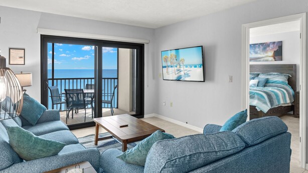 A modern living room with a sofa, a coffee table, and a view of the ocean through a sliding glass door. - Riviera Club 9th floor Direct Beach Front IAN UPDATED AND READY!!! (Fort Myers Beach)