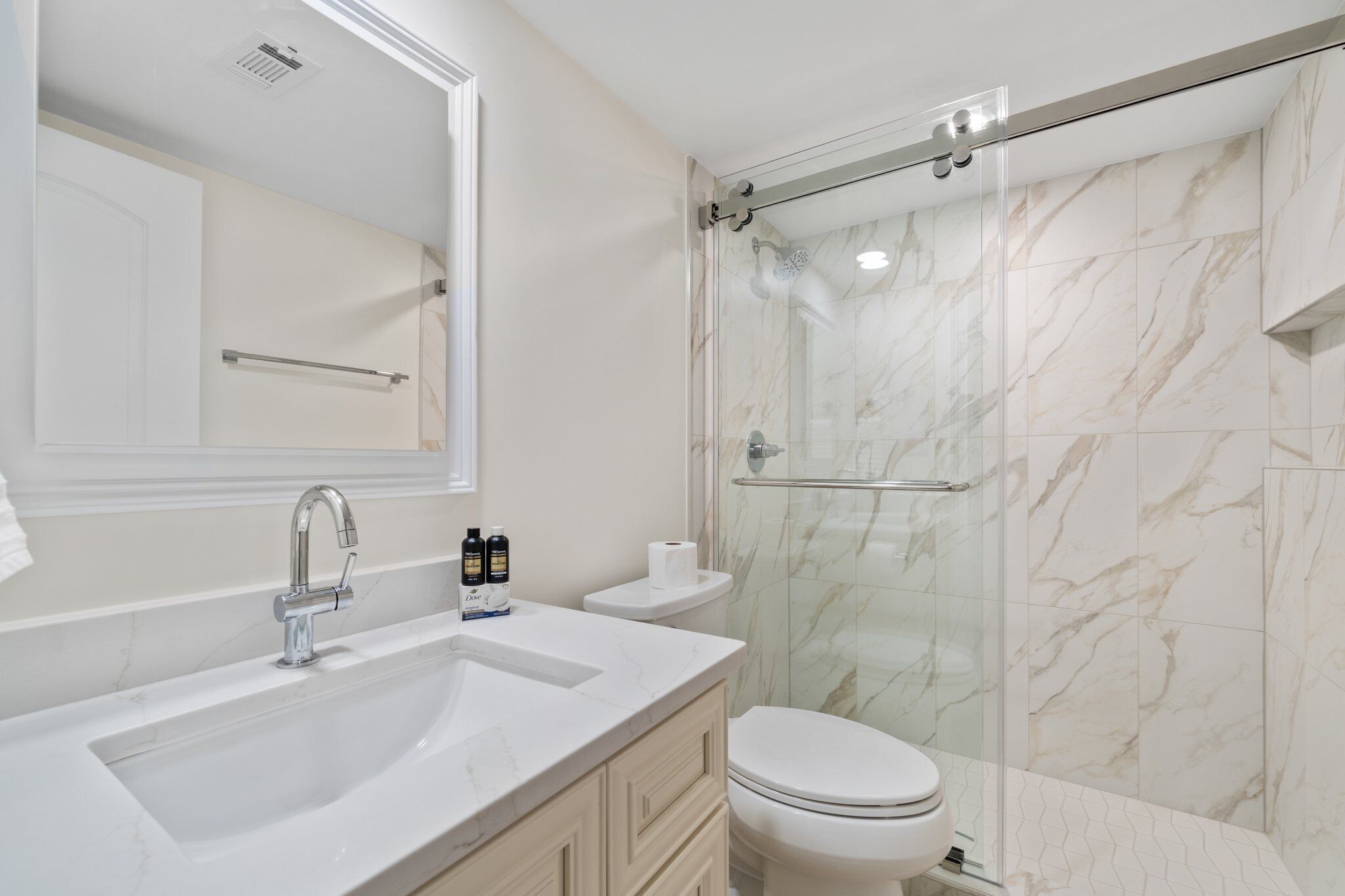 Une salle de bain moderne avec un lavabo en marbre, une douche à parois de verre et des toilettes.