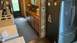 Eine kleine Küche mit Holzausstattung, einem Edelstahlkühlschrank, einer Spüle und einem Herd.