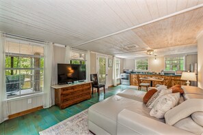 A spacious living room with a large TV, wooden furniture, and a view of the outdoors. - Black Bear (Mentone)