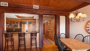 A wooden interior with a kitchen, dining area, and bar stools. - Teton Village Ski-In Ski-Out Crystal Springs Luxury Condominium Jackson Hole WY (Teton Village)