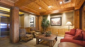 A wooden-paneled room with a sofa, armchairs, a coffee table, and a potted plant. - Teton Village Ski-In Ski-Out Crystal Springs Luxury Condominium Jackson Hole WY (Teton Village)