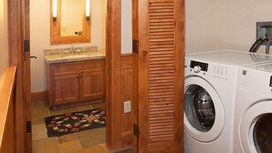 A laundry room with a washing machine, a wooden door, a mirror, and a shelf with towels. - Teton Village Ski-In Ski-Out Crystal Springs Luxury Condominium Jackson Hole WY (Teton Village)