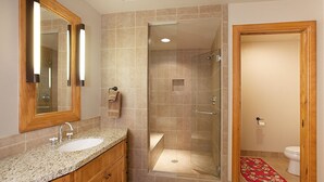 Un baño con dos lavamanos, ducha con cerramiento de vidrio y tocador de madera.