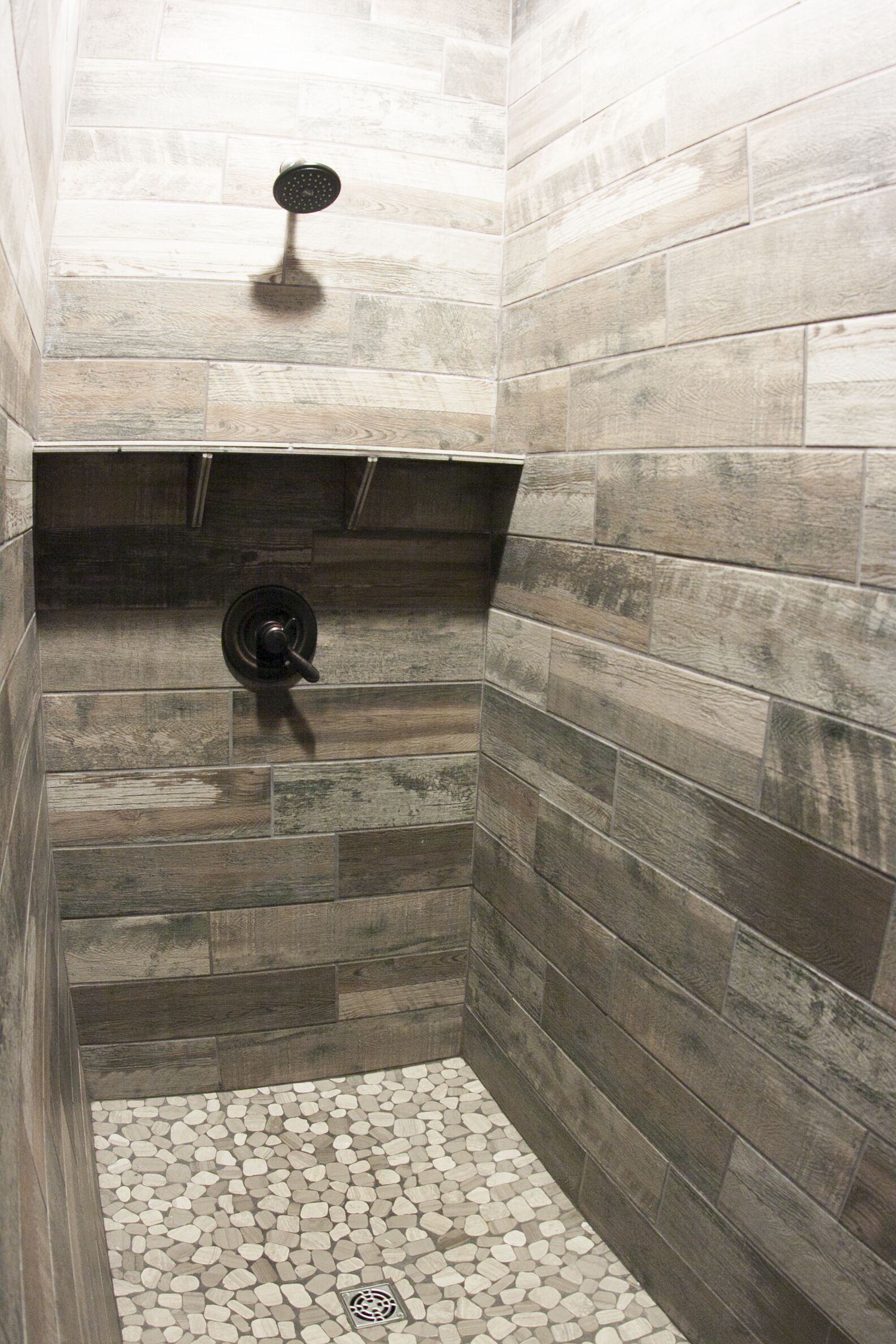 Eine Dusche mit gefliestem Boden und Duschkopf.