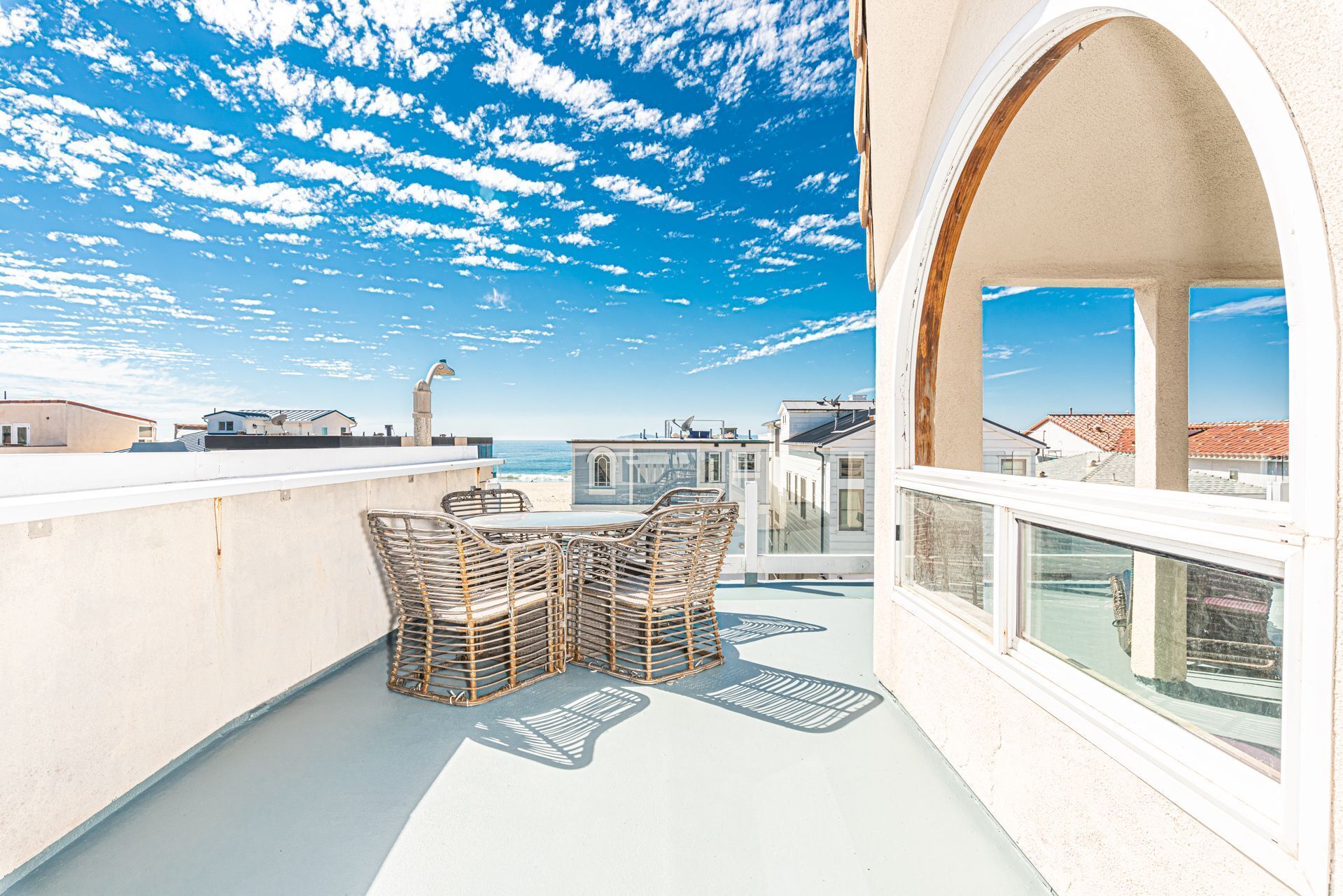 A rooftop terrace with a table and chairs, overlooking a beach and other buildings.