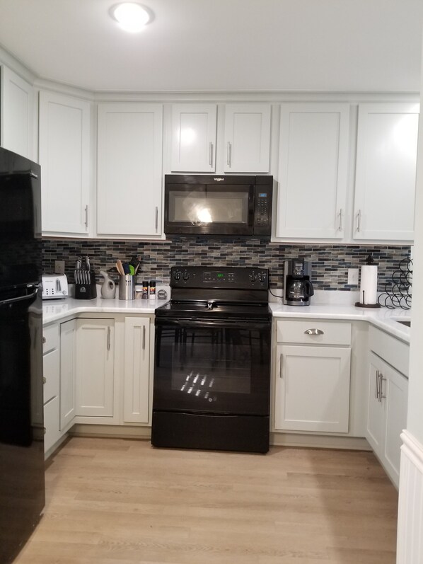 A kitchen with white cabinets, a black microwave, a black stove, and a black refrigerator.