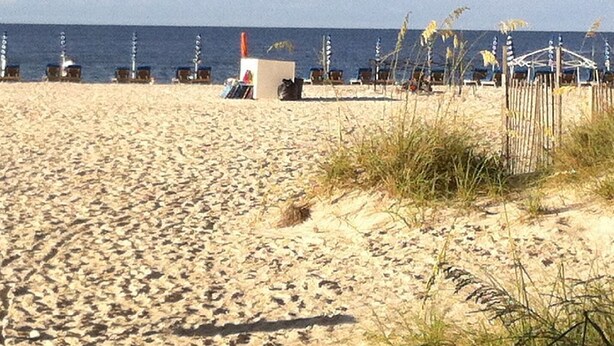 A sandy beach with beach huts and umbrellas. - Welcome to your affordable beach vacation (Gulf Shores)