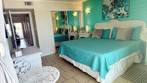 A bedroom with a bed, a chair, a table, a ceiling fan, and a wall with artwork. - Third Floor Private Beach Terrace (Fort Walton Beach)