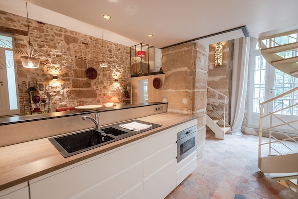 A modern kitchen with a stone wall backsplash, a built-in oven, and a large window.