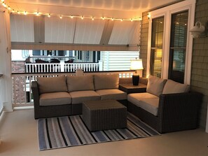 Relax in this inviting outdoor seating area with a sofa, chair, and side table, set amidst a charming ambiance.