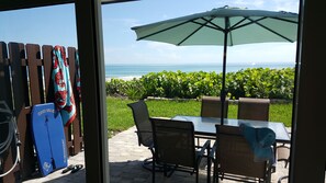 Un patio al aire libre con una mesa, sillas y una sombrilla grande, con vista al océano.