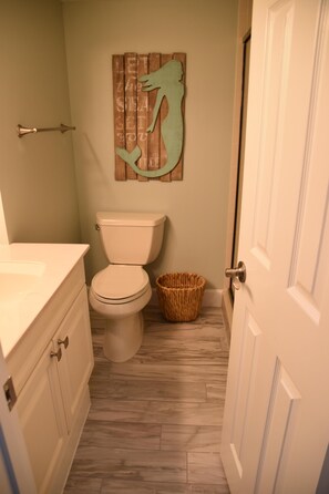 Un baño con inodoro, una cesta de mimbre y un adorno de pared de madera.