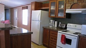 Une cuisine équipée d’un réfrigérateur, d’une cuisinière, d’un four à micro-ondes et de meubles de rangement en bois.