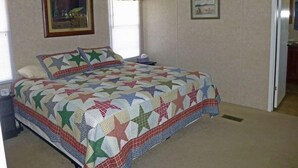 Une chambre à coucher avec un lit, deux fenêtres et deux tableaux encadrés accrochés au mur.