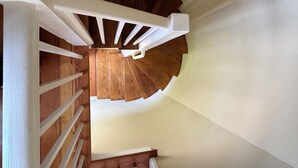 Eine Holztreppe mit weißen Geländern, die zu einer Zwischenebene führt.