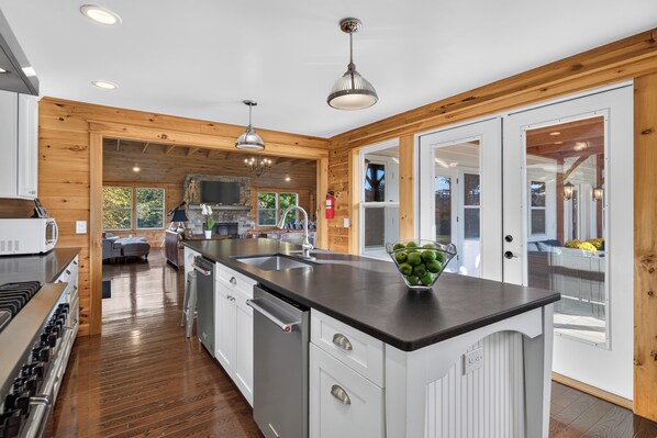 A modern kitchen with a central island, stainless steel appliances, and a stone fireplace.